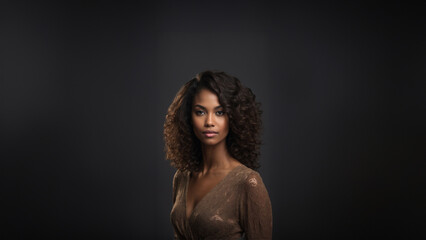 Fototapeta premium Stunning young Black woman with flawless skin and natural beauty. Brunette model with neat hair, gazing confidently at camera. Studio shot, perfect for beauty and cosmetic campaigns.