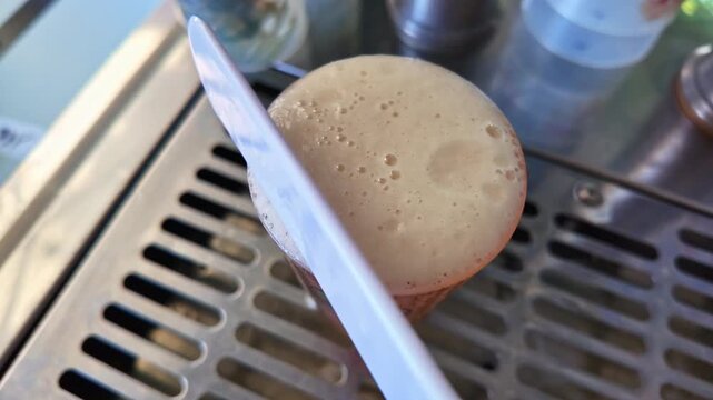 Close-up view about a full glass of beer and removing its foam with an appropriate tool, France.