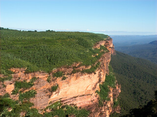Morning sunlight illuminates a sheer cliff at Blue Mountains National Park of New South Wales Australia