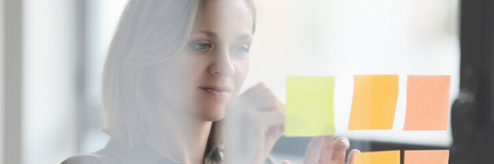 Manager putting stickers note on transparent glass wall in office