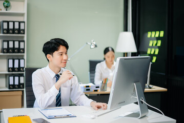 Two young Asian professionals engaged in teamwork and business discussions in modern office embodying corporate