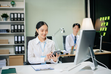 Two young Asian professionals engaged in teamwork and business discussions in modern office embodying corporate