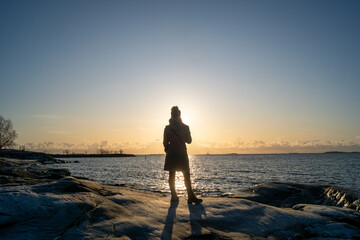 Fototapeta premium lonely blond woman on the beach in Helsinki Finland on a cold winter day watching sunset