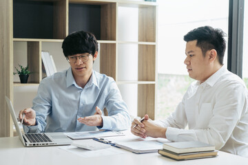 Businessman explaining numeric graphs on computer to colleagues.