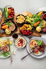 Table with grilled food. Pizza, corn, tomatoes, peppers, cooked meat. BBQ time