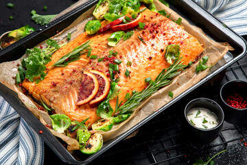 Cooked seafood on a black background. Baked salmon with onion, lemon, pomegranate juice