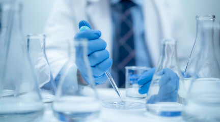 Scientist analyzing and dropping a sample into a glassware, experiments containing chemical liquid in laboratory on glassware