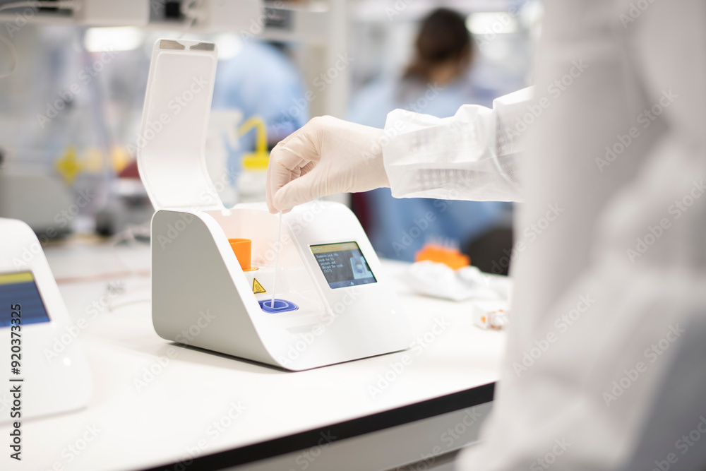 Wall mural lab technician placing swab into point-of-care testing machine f