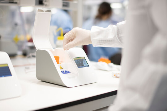 Lab technician placing swab into point-of-care testing machine f