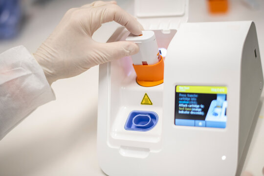 Lab technician placing cartridge into point-of-care virus testin