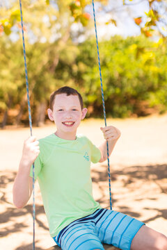 Teenage boy sitting on a rope swing