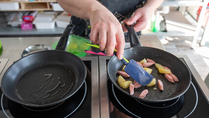 The chef fries potatoes with sausages in a frying pan. 