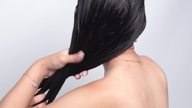 Beautiful young Asian woman with long hair is getting her hair washed using conditioner.