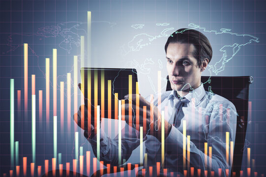 Attractive young businessman sitting and using tablet with downward forex chart on blurry background. Financial recession and crashing market concept. Double exposure.