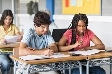 African American girl and caucasian guy students talking about class work learning together at...