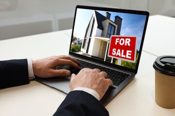 Man looking for house on real estate market website at table, closeup