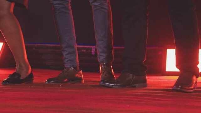 Dancing shoes of a couple, couples dancing traditional latin argentinian dance milonga in the ballroom, tango salsa bachata kizomba lesson, festival on wooden floor, purple, red and violet lights