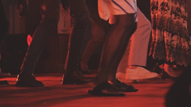 Dancing shoes of a couple, couples dancing traditional latin argentinian dance milonga in the ballroom, tango salsa bachata kizomba lesson, festival on wooden floor, purple, red and violet lights