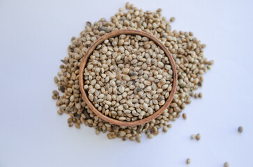 Hemp seeds in wooden plate on white background