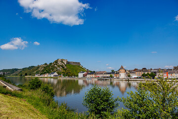 Obraz premium Panoramic landscape of Meuse river with Charlemont fortress on hill and cityscape of Givet town in background, medieval and old buildings, sunny day with blue sky in Ardennes department, France