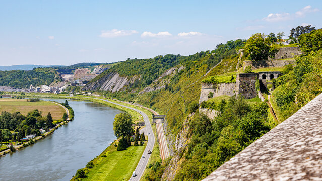 Panoramic view of Meuse river seen from Charlemont fortress, country road and railway tracks stone walls, trees on hill and horizon in background, sunny summer day in the Ardennes department, France - Powered by Adobe