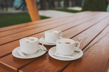 cup of black coffee on the wooden table outdoor cafe. three cups of coffee on the table. 