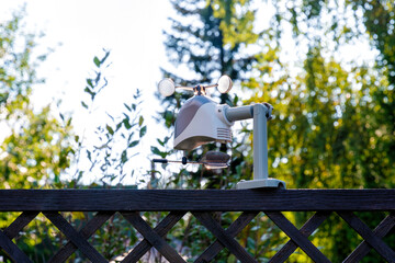 Wireless weather station is mounted on a wooden fence. Personal weather forecasting device