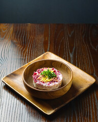 Traditional Russian Shuba Salad with Herring in Wooden Bowl on Rustic Table.