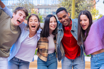 Five young multiracial friends taking a selfie portrait together outdoors