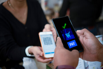 Close-up of two people using smartphones for digital payment through QR code scanning, illustrating modern contactless transactions.