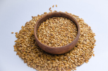 white flax seeds in a wooden round bowl on a light background