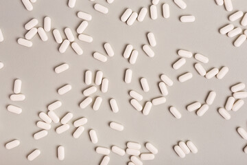 Many white pills from above on a light background. Medicines flat lay. Background of a big amount of white tablets.