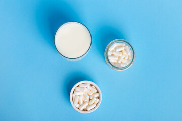 Lactase tablets, yogurt containing lactose and a wooden spoon from above on a blue background. lactase tablets for assimilation of lactose from dairy products. Lactose intolerance.