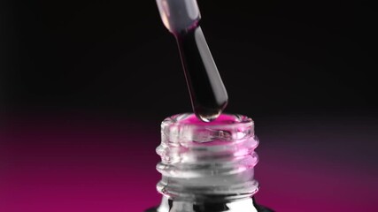 Gel nail polish, transparent shellac UV gel bottle, brush, varnish, manicure concept, slow motion. Manicure salon. Black bottle over black background, close up