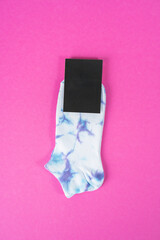 Tie dye socks with black label on pink background. mockup with blank label