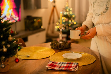 Girl with white pajamas in the living room of her house having tea, one Christmas