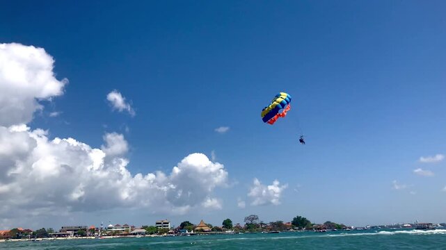 A tourist doing parasailing on a beach, summer water sport fun