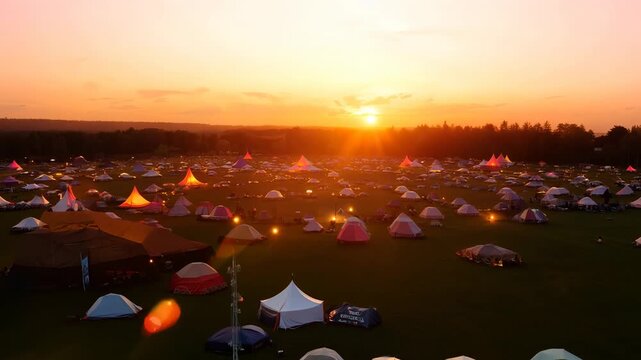 Sunset view of a large outdoor music festival with tents at the campsite