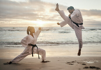 People, karate and beach with jump for martial arts training, fighting practice or self defense in nature. Man, woman or opposing sides in air kick on ocean coast for taekwondo, battle or challenge