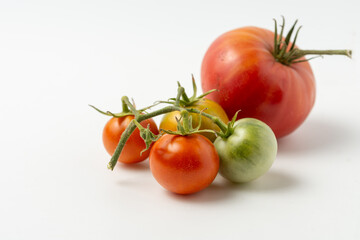 Ripe and green natural tomatoes on a white background. Close up.
