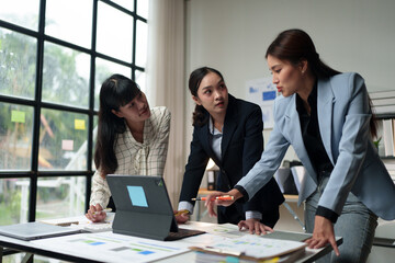Team of Asian businesswomen standing and discussing real estate business projects on laptops Modern meeting in the office Financial online business idea online marketing.
