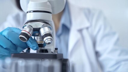 Scientist using microscope in laboratory. Close-up of a researcher's hands adjusting a modern microscope in a lab setting. Science concept