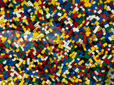A pile of colorful legos in a pattern. The colors are red, yellow, green, blue, and white