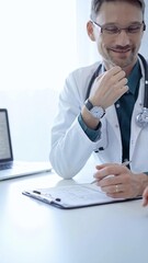 Obraz premium Doctor and a patient. The physician, wearing a white medical coat over a green shirt, gesturing with his hands during a consultation in the clinic. Medicine concept