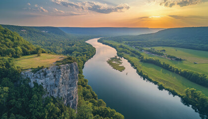 Sunset illuminating river winding through green valley with cliff overlook