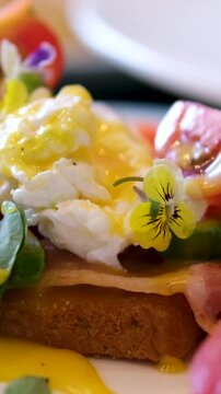 Eggs Benedict with bread and tomato on a plate with becon morning sandwich. Egg benedict with hollandaise sauce and smoked salmon on toast
