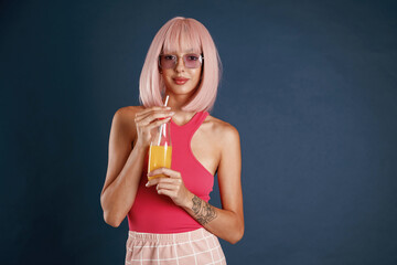 Pink hair, with orange juice. Beautiful young woman is against background