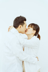 A middle-aged Asian couple, with the woman being pregnant, shares a loving embrace, smiling with happiness and anticipation for their soon-to-arrive baby, symbolizing family togetherness and joy.