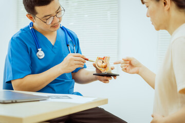 A male Asian pediatrician in a white lab coat conducts a prenatal checkup for a middle-aged...