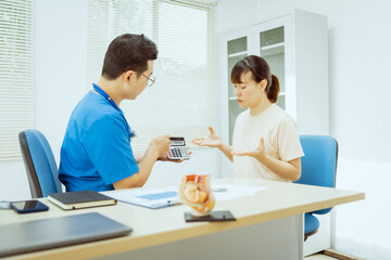 A male Asian pediatrician in a white lab coat conducts a prenatal checkup for a middle-aged...